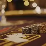 Mastering Edge Sorting in Baccarat: A Guide to This Controversial Technique Close-up of Poker Chips on a Casino Table A detailed close-up image of a stack of casino chips in varying colors, placed on a green casino table under soft, blurred lighting. In the foreground, playing cards are partially visible, while the background is filled with warm, glowing bokeh effects, adding to the luxurious casino ambiance.